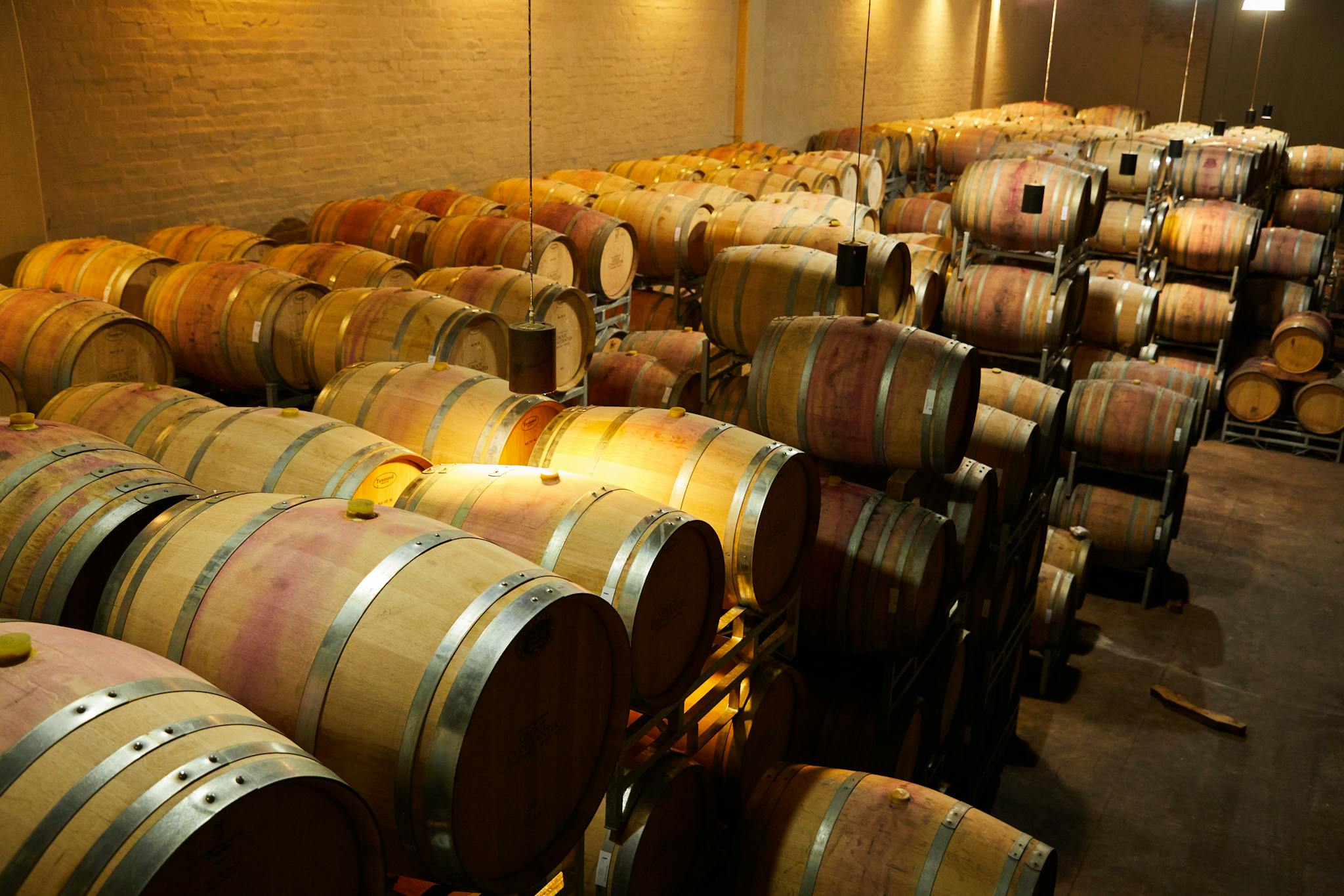 A warm-toned view of wine barrels stored in a winery cellar, ready for fermentation.