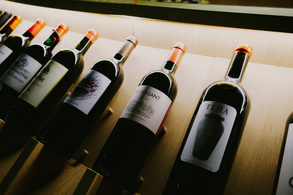 Close-up view of assorted wine bottles on a stylish wooden display shelf.