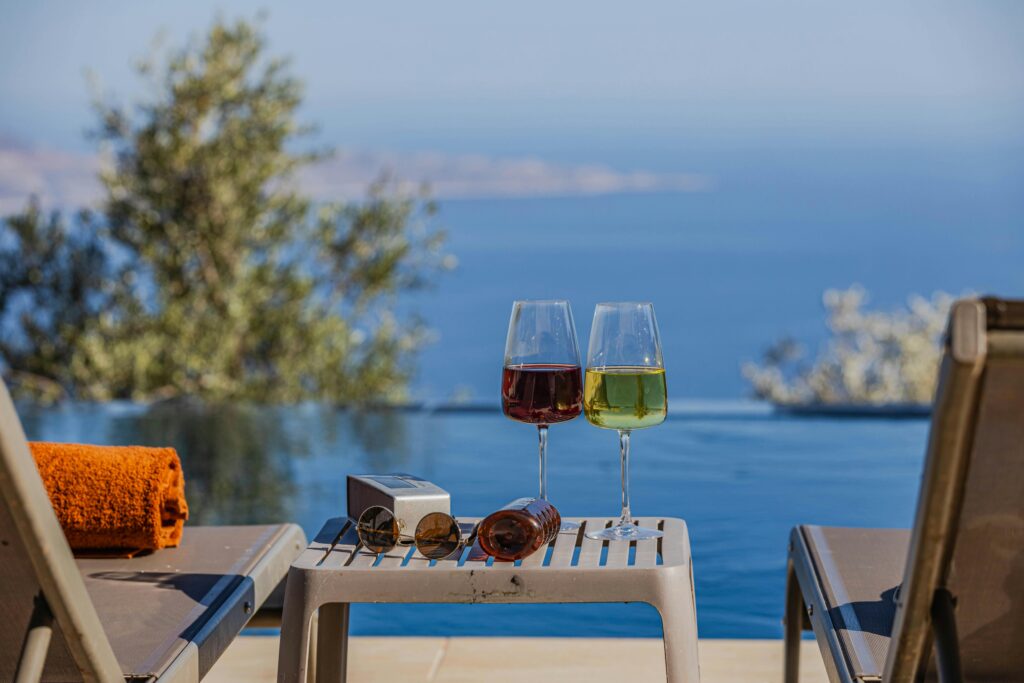 Enjoy a tranquil moment by the pool with wine and serene ocean views. Perfect for a luxurious vacation.