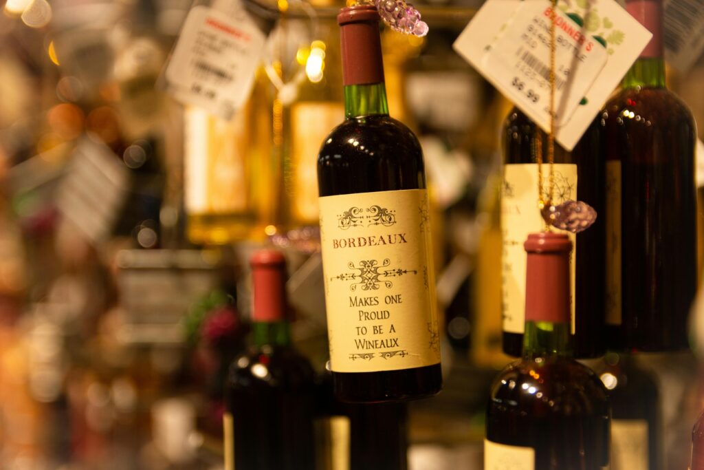 Close-up of Bordeaux wine bottles hanging in a liquor store with price tags.